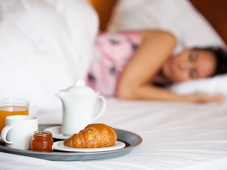 Kvinde der sover med morgenmad på sengen